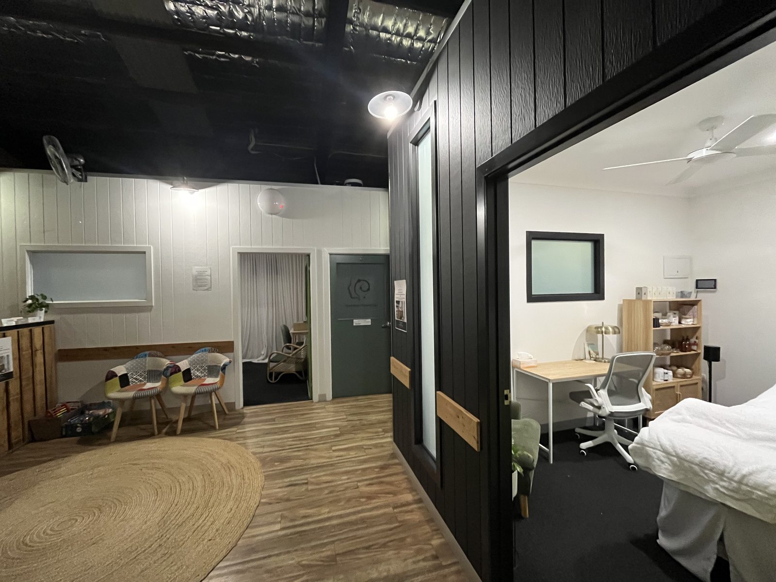 Inside a practitioner room with a desk, chair and treatment table